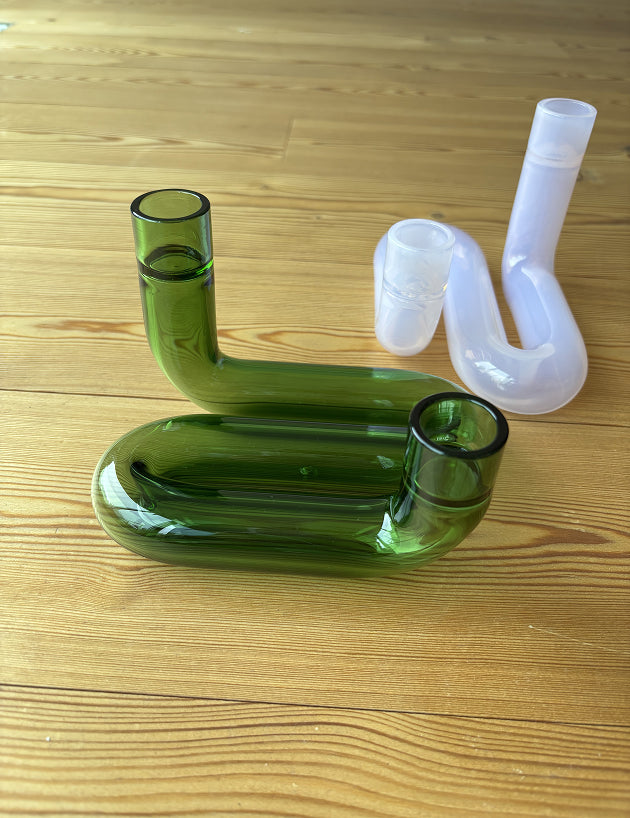 zwei Kerzenhalte auf Holzboden, einer grün, einer rosa