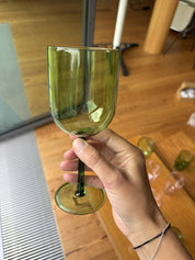 Eine Hand hält ein Weinglas in grün