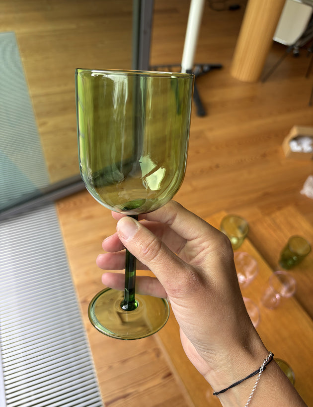 Eine Hand hält ein Weinglas in grün