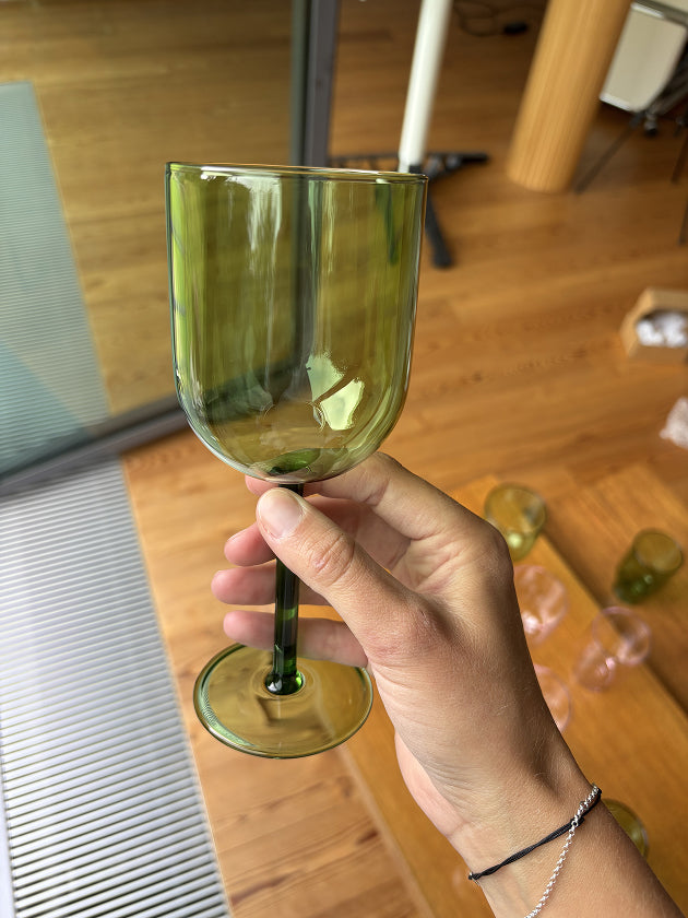 Eine Hand hält ein Weinglas in grün