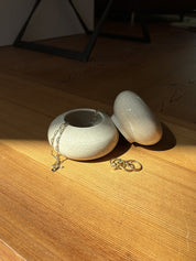 Eine Dose auf Holzfußboden, Deckel ist geöffnet und Schmuck ist in der Dose