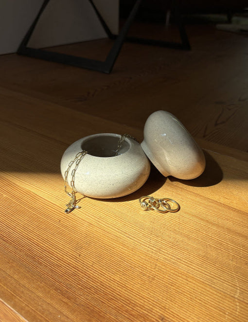 Eine Dose auf Holzfußboden, Deckel ist geöffnet und Schmuck ist in der Dose